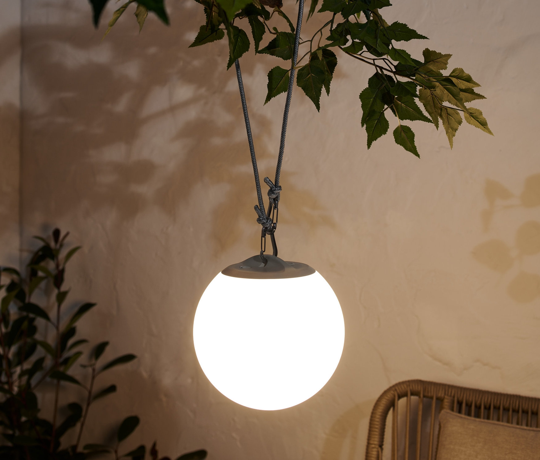 LED závěsné svítidlo na dobíjecí baterie visí z větve stromu.