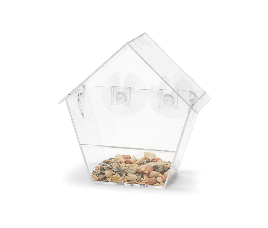 Průhledné krmítko pro ptáky na okno plné zrní.