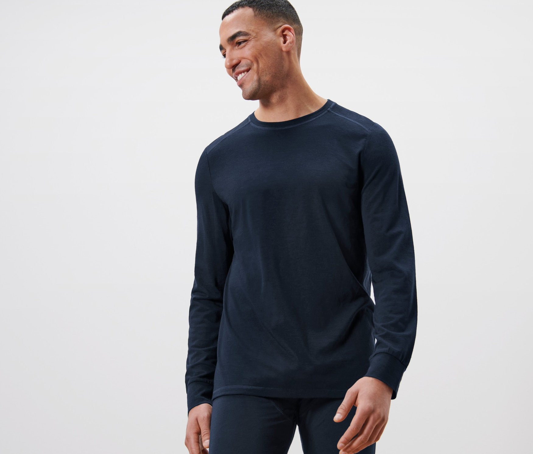 Muž se usmívá a má na sobě tmavě modré triko s dlouhým rukávem s certifikací RWS.