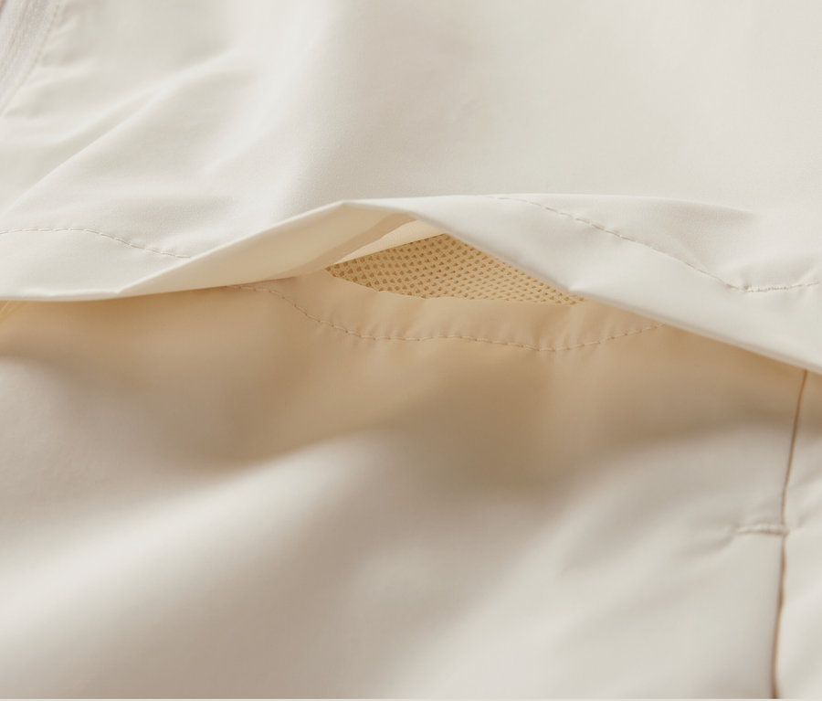 Detail krémové větruvzdorné běžecké bundy.