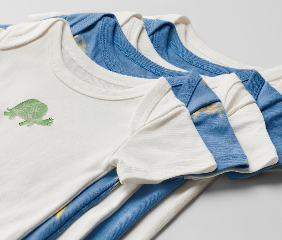 Detail pěti dětských body s krátkým rukávem. Jedno bílé body má obrázek želvy.