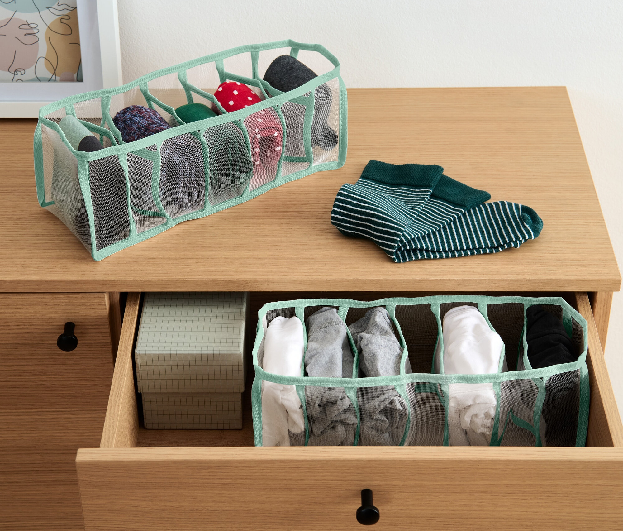 Dva organizéry do šatních skříní, jeden na komodě a jeden v otevřené zásuvce, oba obsahují různé ponožky.