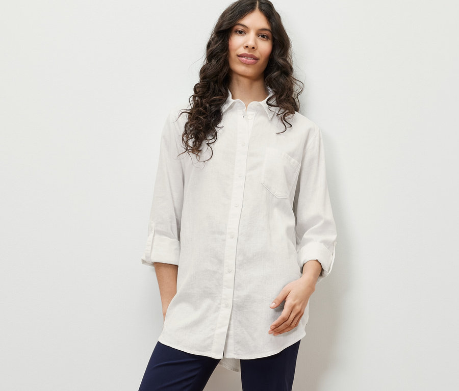 Žena pózuje v dlouhé lněné halence, bílá.