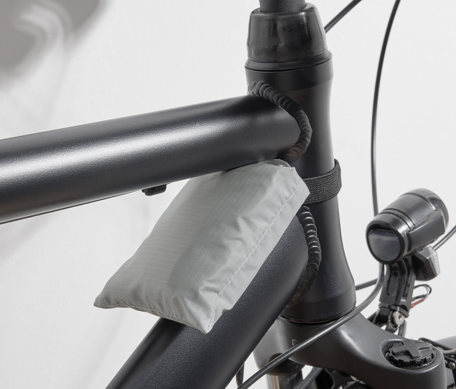 Šedá nákupní taška na kolo připevněná k rámu kola.