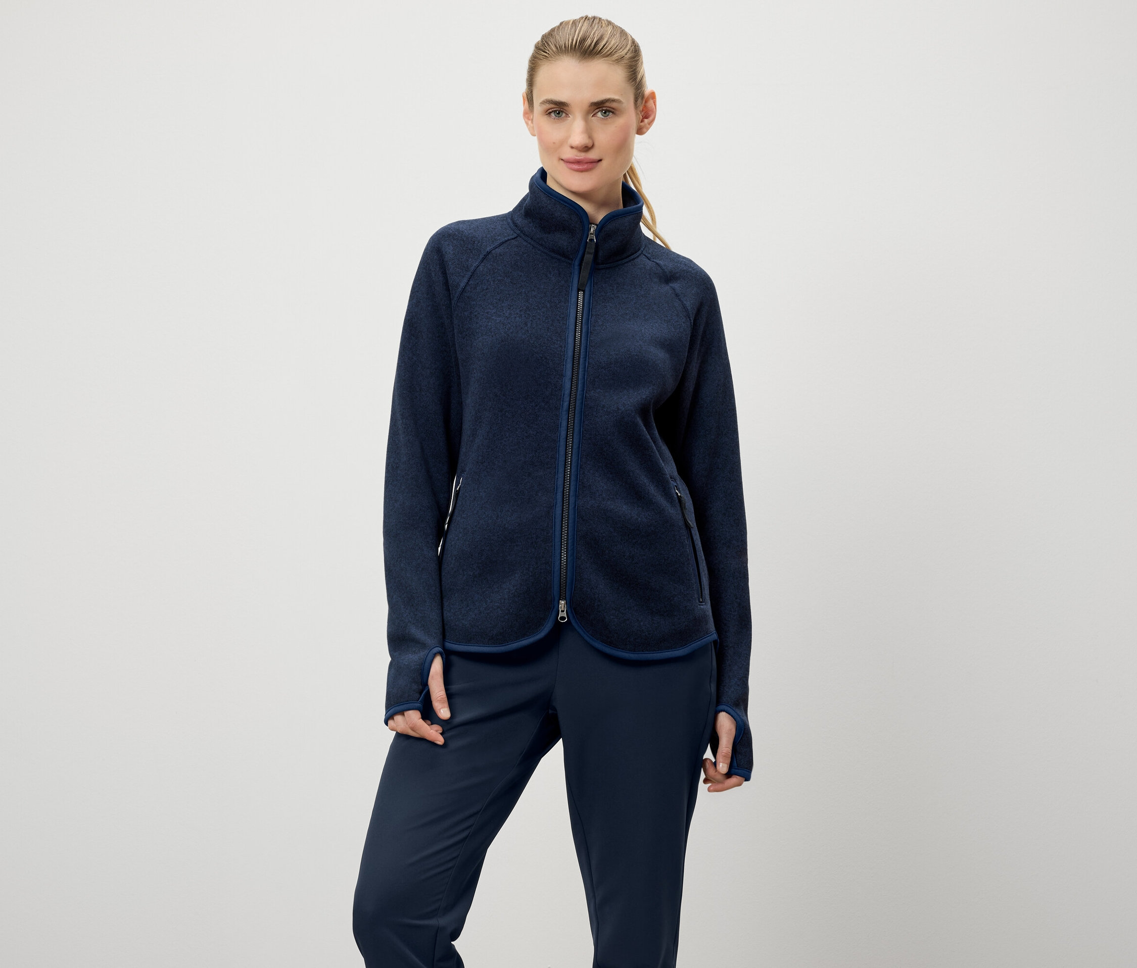 Žena má na sobě modrou fleecovou bundu na zip a modré kalhoty.