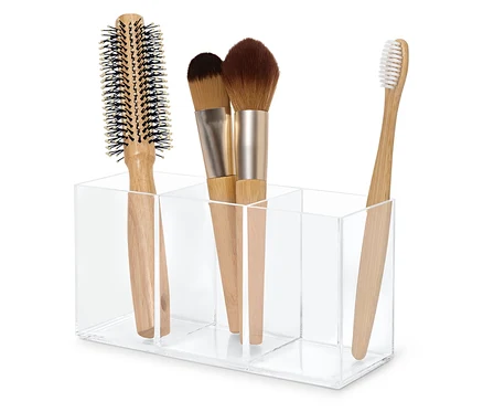 Kartáč na vlasy, dva štětce na make-up a zubní kartáček v průhledném akrylovém organizéru.