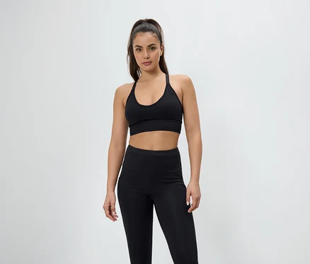 Žena pózuje ve sportovní podprsence a legínách černé barvy.