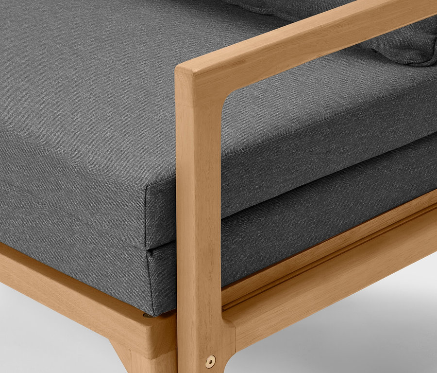 Detailní pohled na rozkládací lounge pohovku s šedým čalouněním a světlým dřevěným rámem.