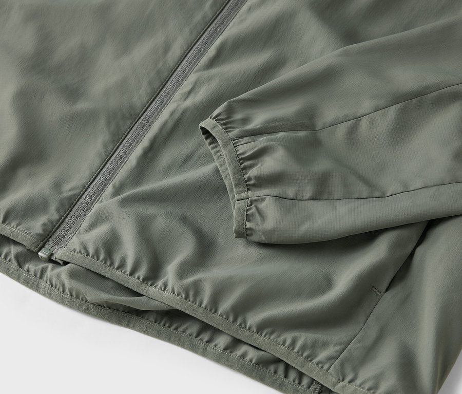 Detail olivové bundy na zip.