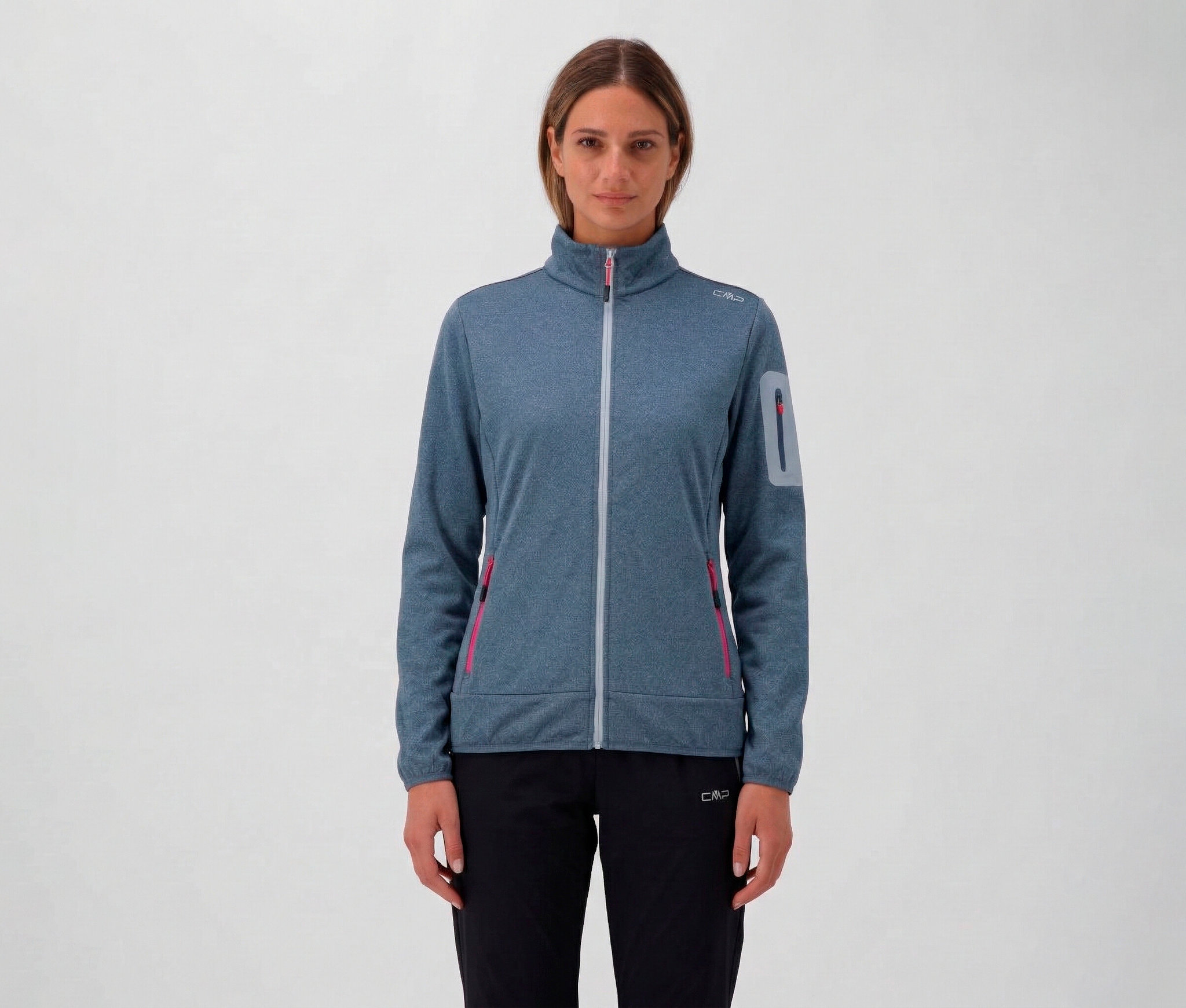 Žena v černých kalhotách a modré dámské bundě CMP se zipem a kapsami.