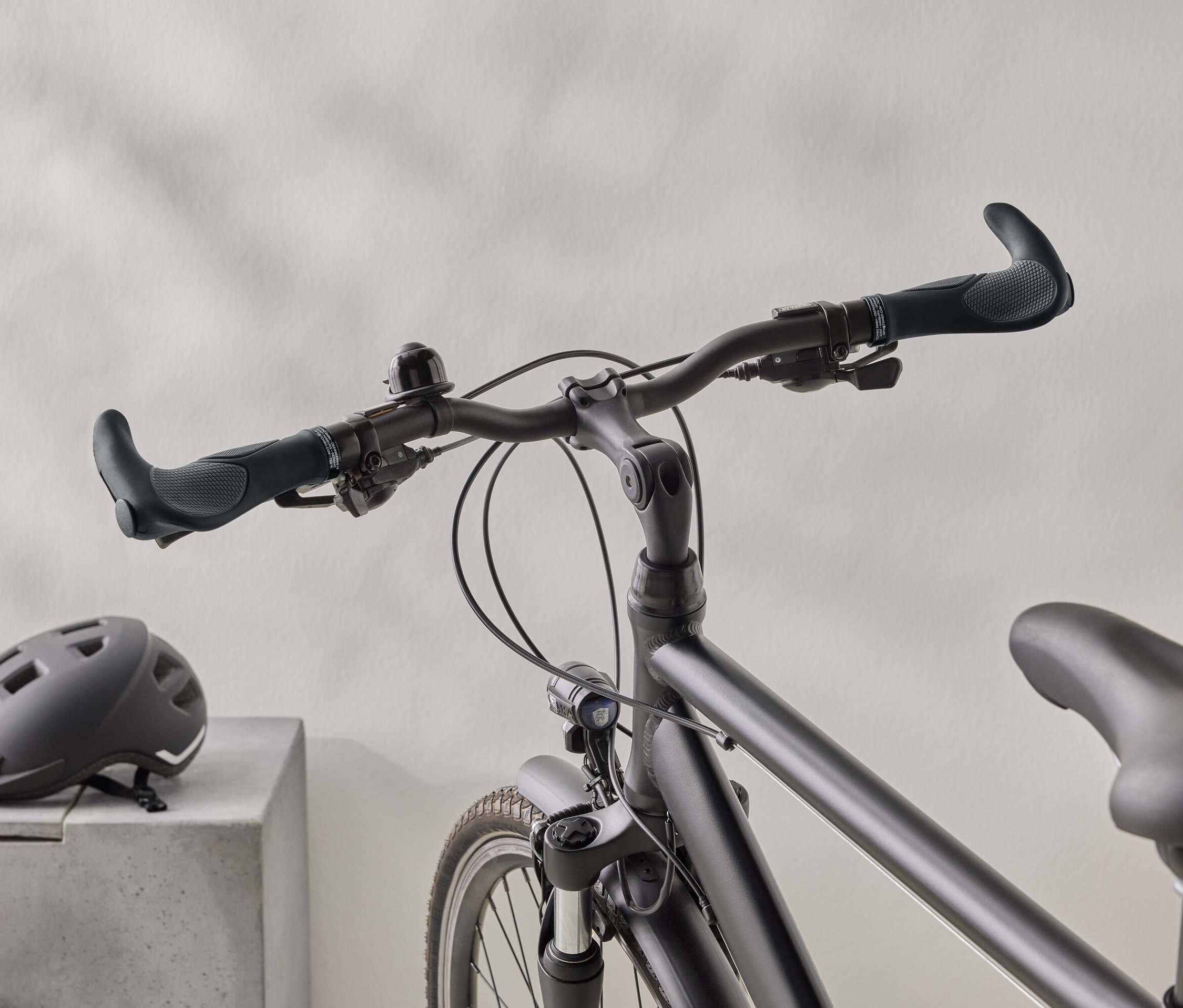 Detailní záběr matného černého kola s černou helmou na betonovém povrchu v pozadí.