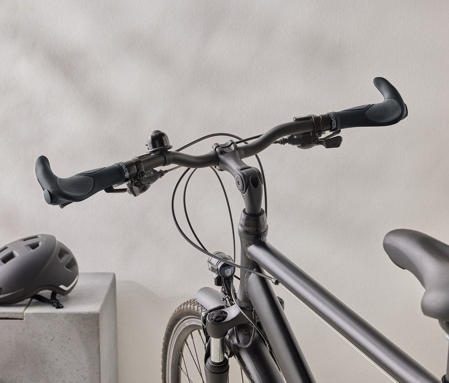 Detailní záběr matného černého kola s černou helmou na betonovém povrchu v pozadí.