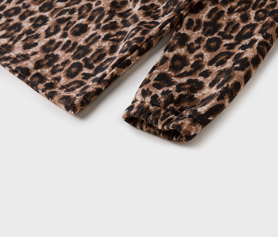 Detail rukávu s leopardím vzorem a nařaseným lemem na bílém pozadí.