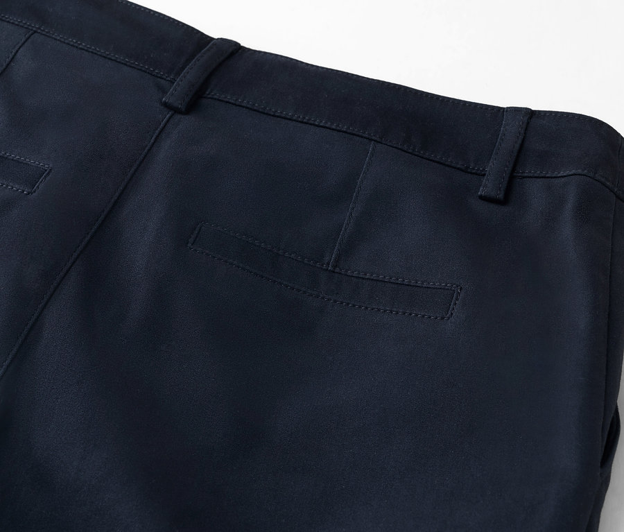 Detailní pohled na zadní část tmavě modrých kalhot se zadní kapsou.