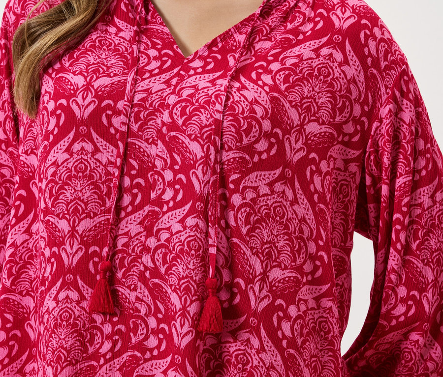 Detailní záběr na červený top s růžovým květinovým vzorem a stahovací šňůrkou.