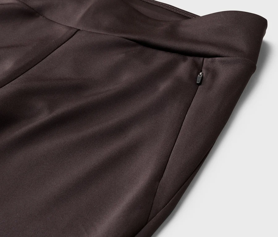Detail hnědých kalhot s kapsou na zip v pase.