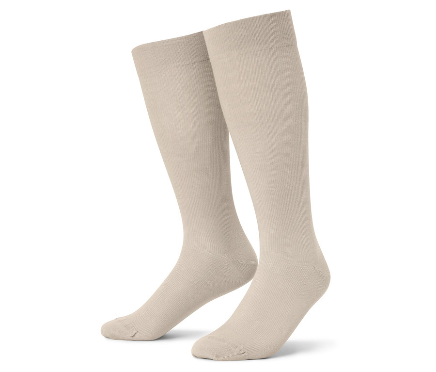 Detailní záběr dvou béžových podkolenek na bílém pozadí.