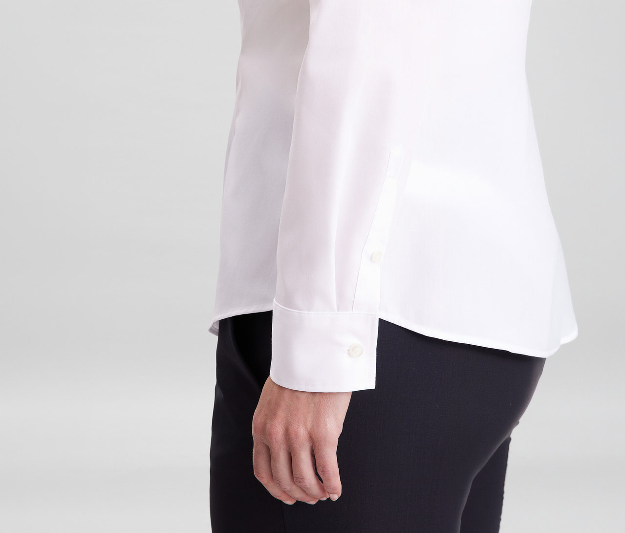 Osoba v bílé halence Seidensticker slim fit non iron a černých kalhotách, viditelný rukáv s manžetou.