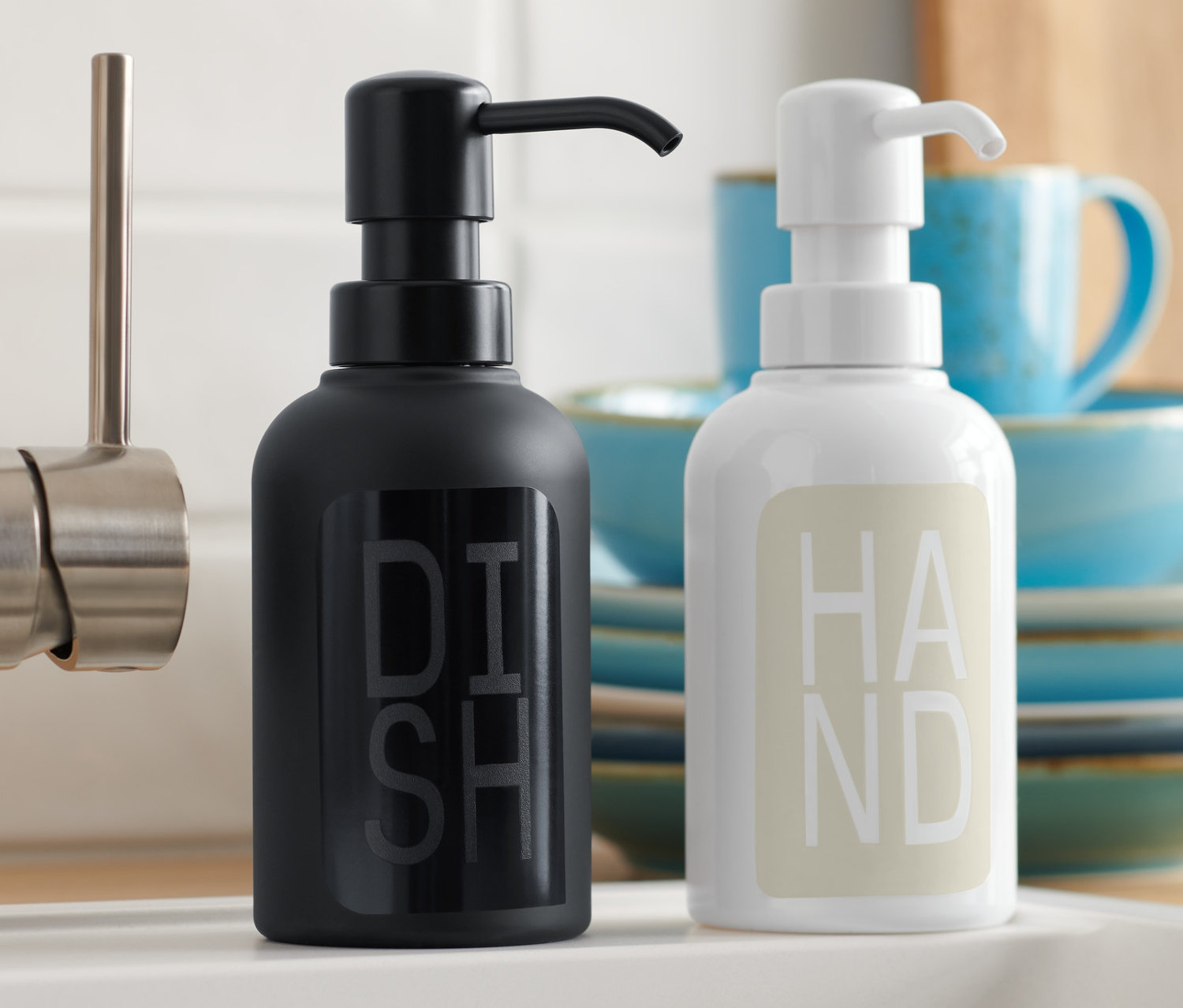 Černý a bílý dávkovač mýdla, 2 ks, stojí u dřezu.