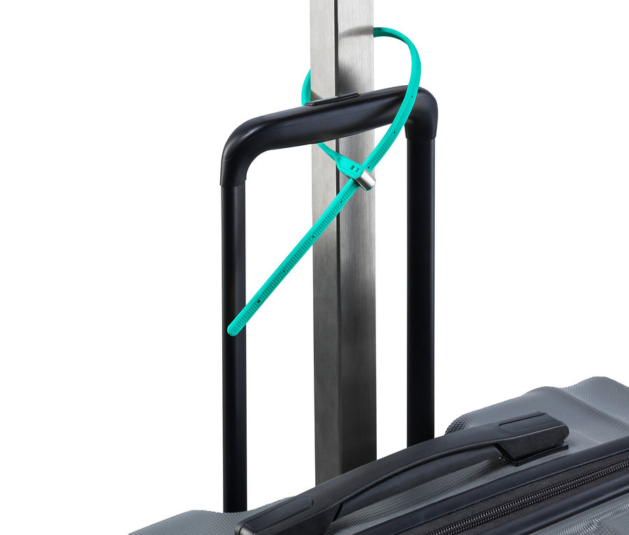 Tyrkysový kabelový zámek je upevněný na rukojeti šedého kufru a stříbrné tyči.