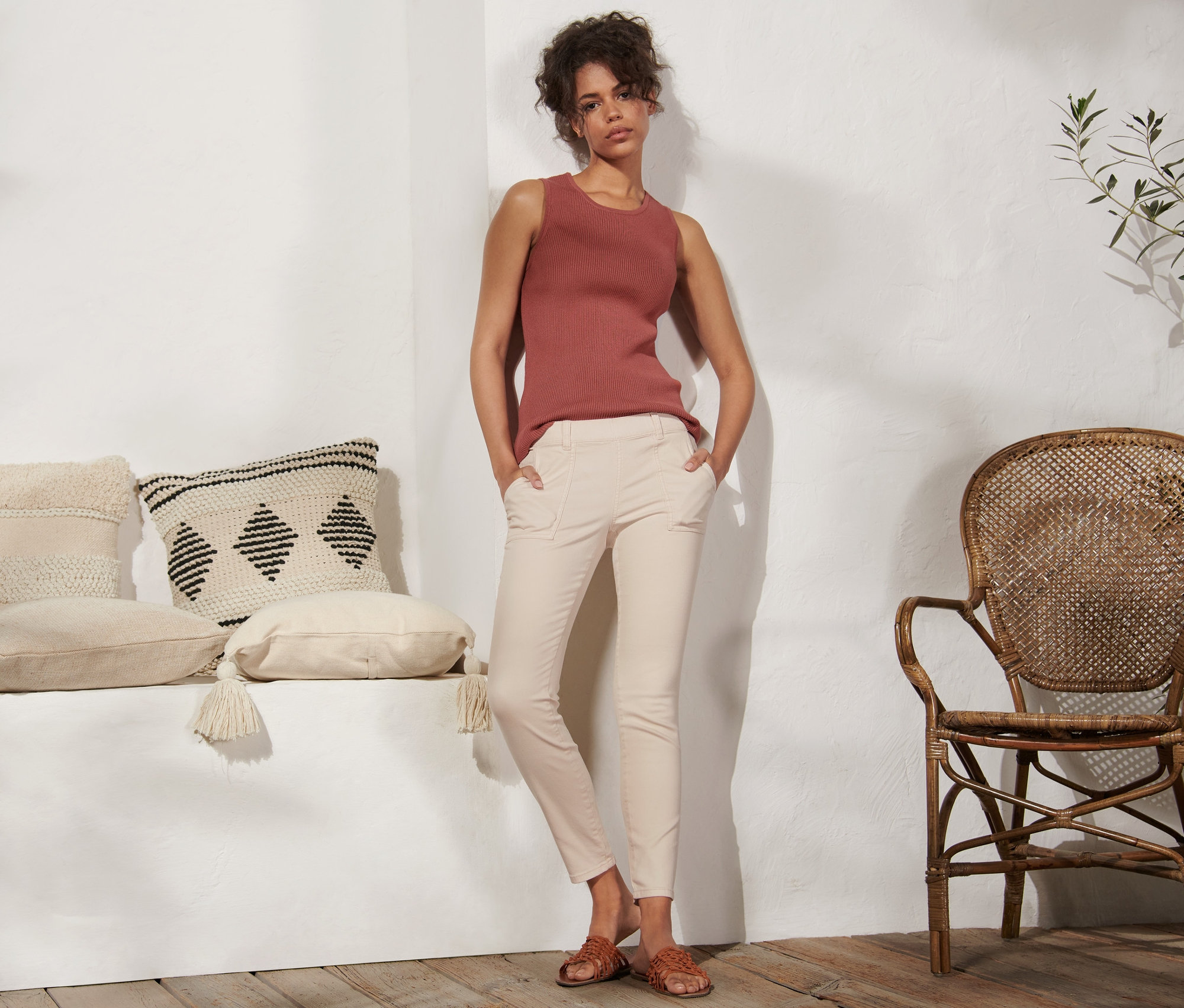 Žena stojí a má ruce v kapsách krémových tregín.
