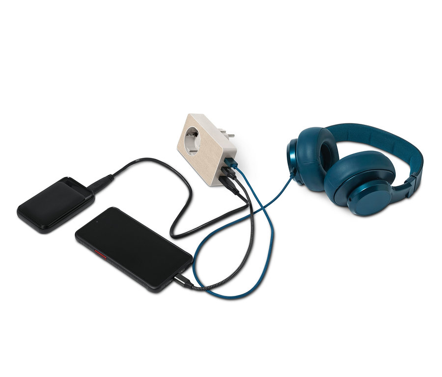 Černý telefon, powerbanka a modrá sluchátka jsou nabíjeny pomocí USB adaptéru 4 v 1.