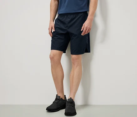 Muž stojí a má na sobě sportovní šortky.