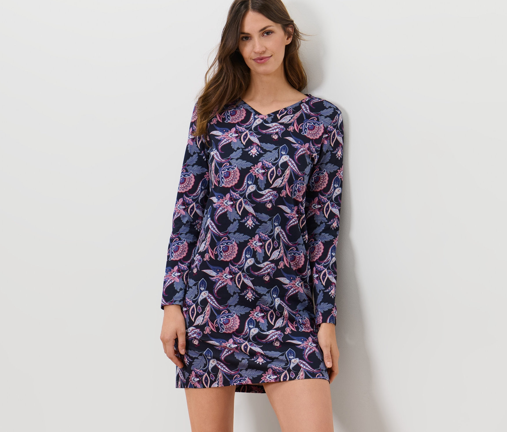 Žena pózuje v noční košili s kašmírovým vzorem.