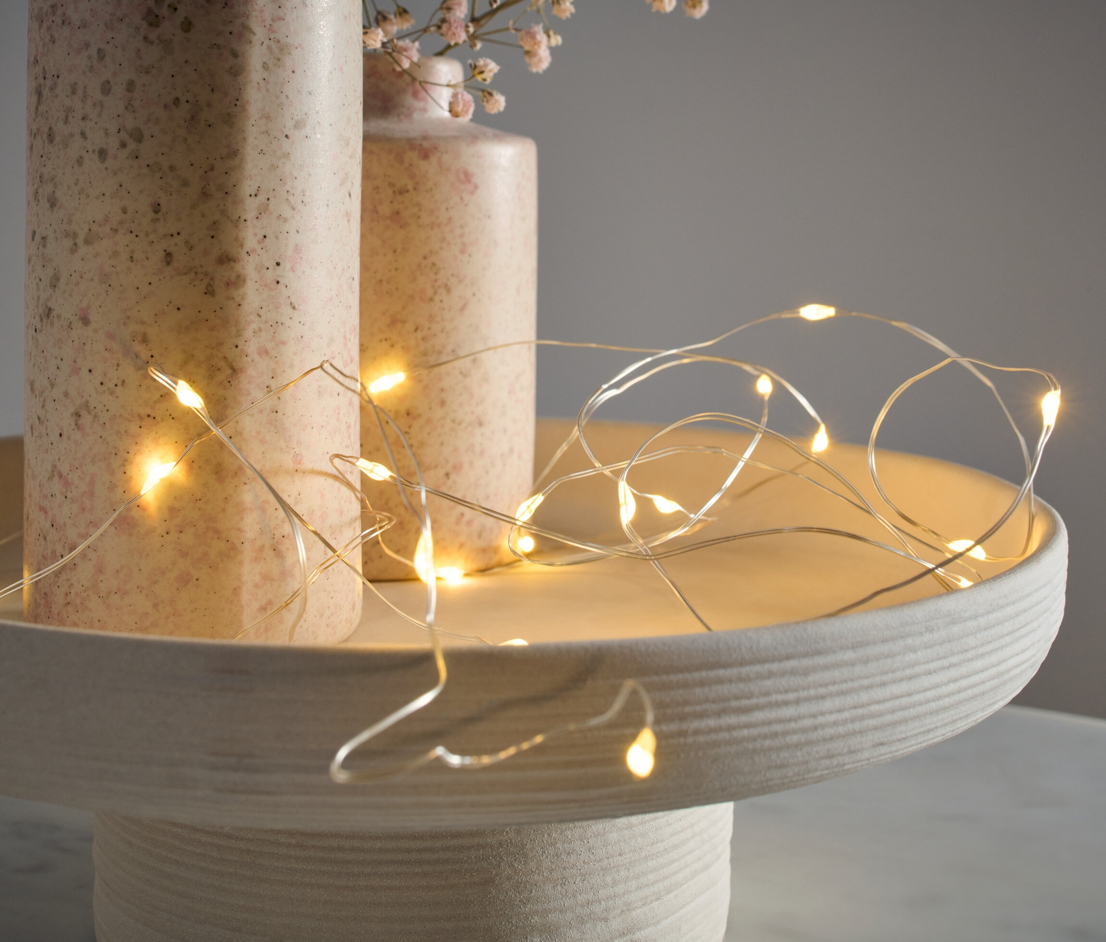 Mikro LED světelný řetěz, kapky, leží na dekorativním podnosu vedle dvou váz.