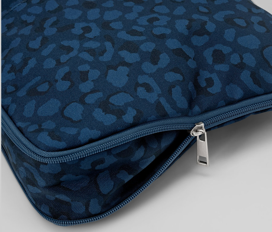 Detail modré bezpečnostní taštičky přes rameno se vzorem a stříbrným zipem.