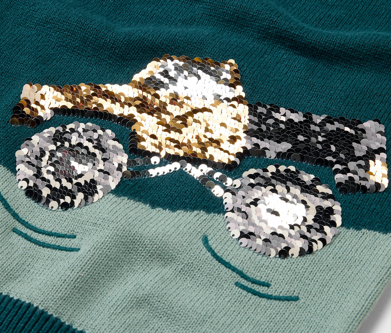 Detailní pohled na dětský pletený svetr s motivem náklaďáku z flitrů.