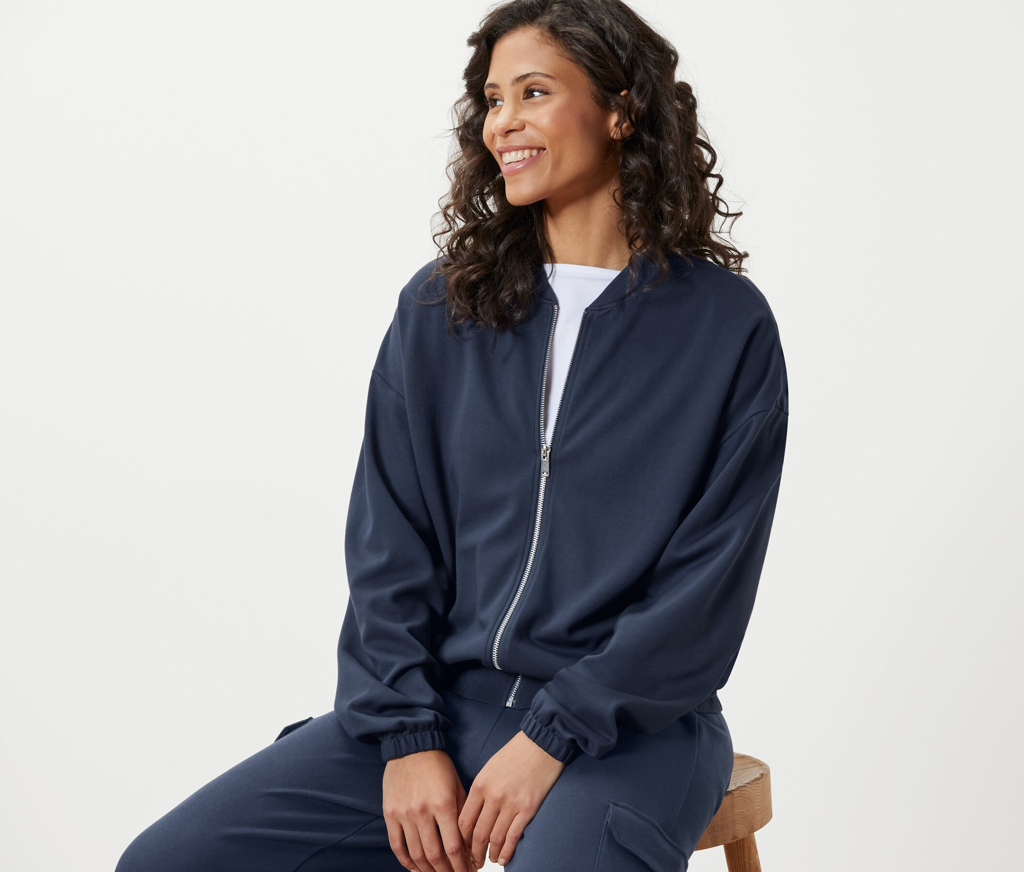 Žena sedí a má na sobě modrou mikinu.