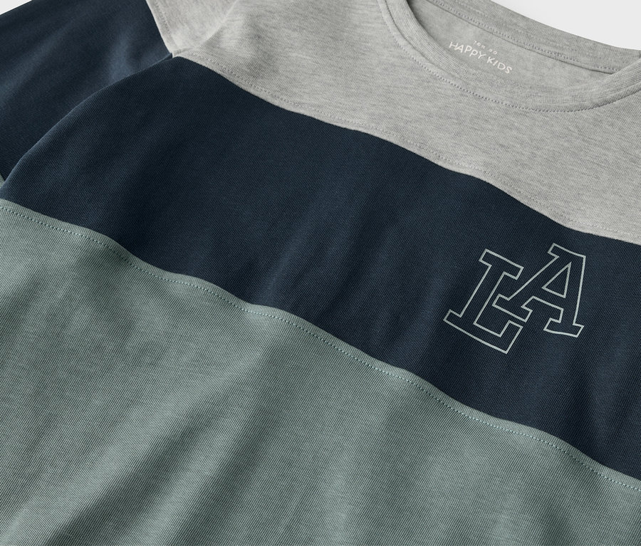 Detail dětského trika s dlouhým rukávem Pevné dětské triko s dlouhým rukávem, které má šedý horní díl, tmavě modrý pruh uprostřed a šedomodrý spodní díl.