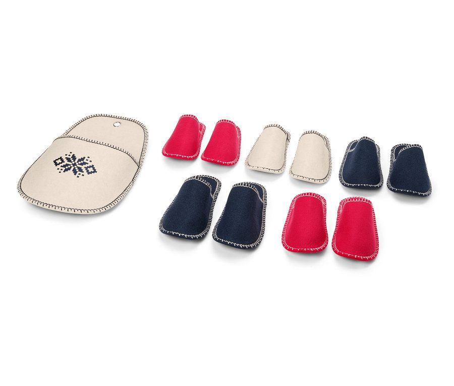 Pouzdro na jehlice s výšivkou vedle sady červených, krémových a modrých chráničů na jehlice.