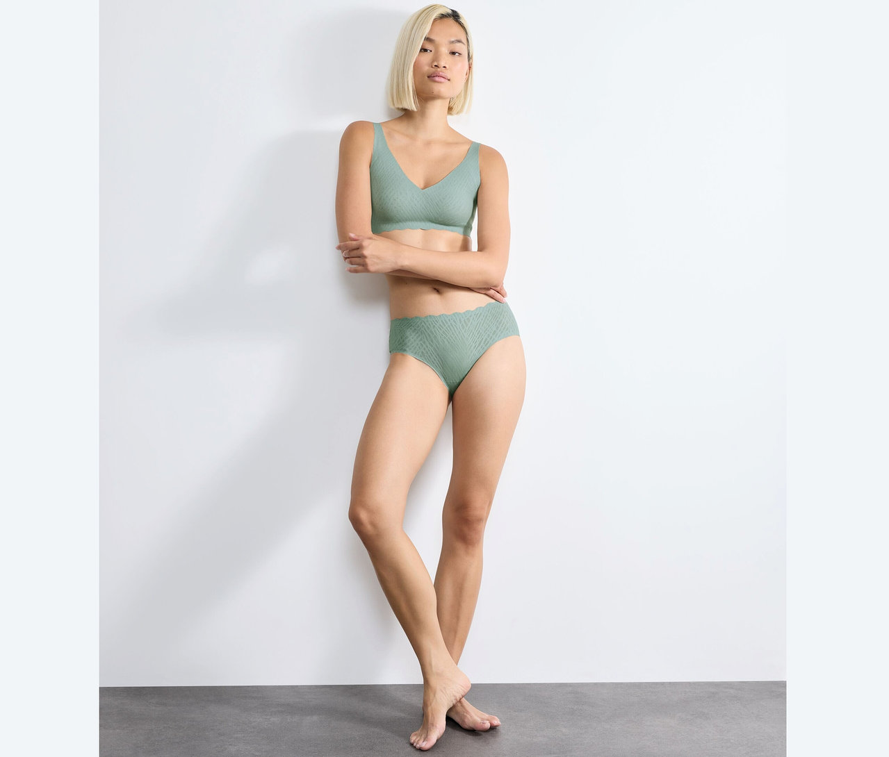 Žena pózuje v měkké podprsence sloggi ZERO Feel Bliss Soft Bra v barvě misty turquoise a odpovídajících kalhotkách.