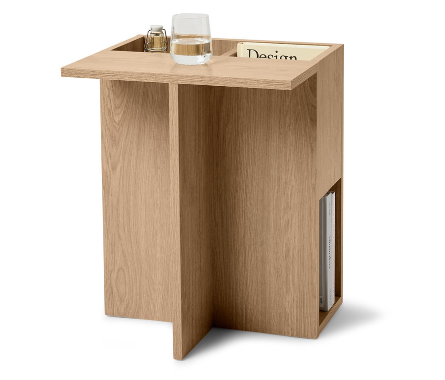 Boční stolek ze světlého dřeva se sklenicí vody, lampou a časopisem.