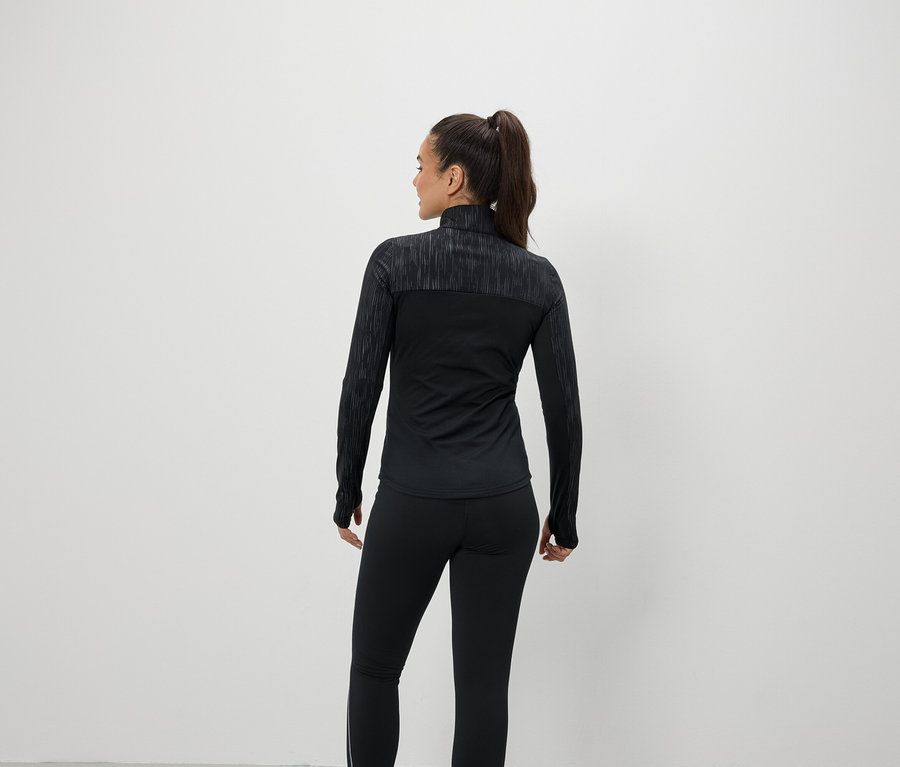 Žena zády k fotoaparátu má na sobě černé sportovní oblečení.