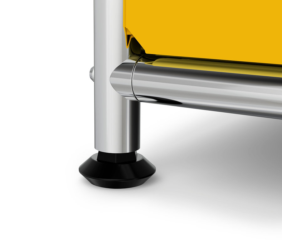 Detail žlutého nábytku s chromovanou nohou a černou patkou.