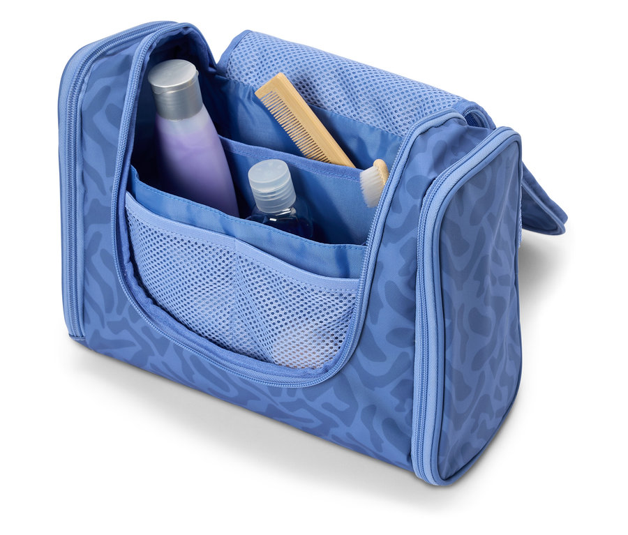 Otevřená světle modrá kosmetická taška s různými cestovními potřebami, jako je šampon, hřeben a zubní kartáček.