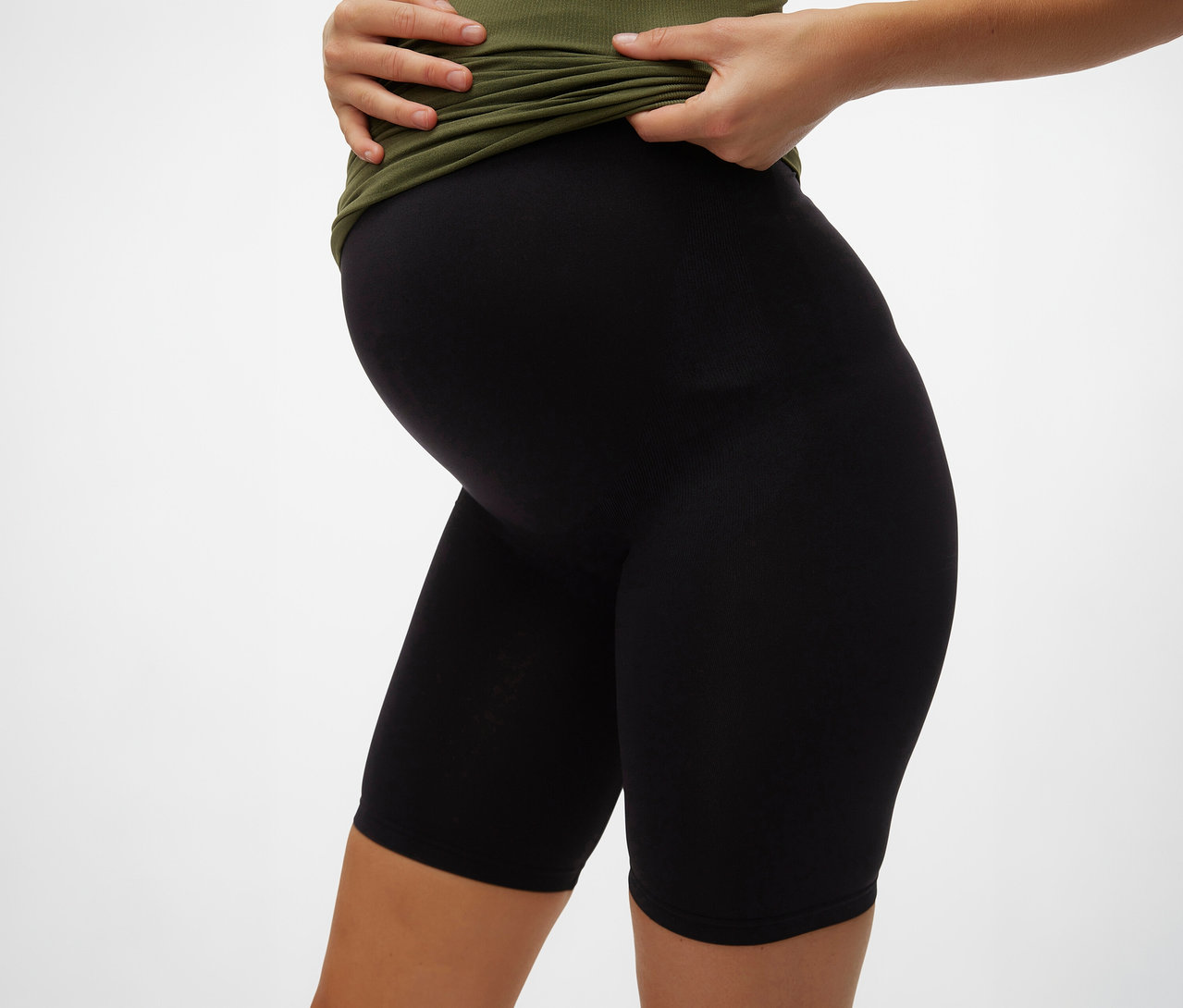 Těhotná žena v olivovém tričku a černých skinny šortkách MAMALICIOUS »MLTIA JEANNE«.