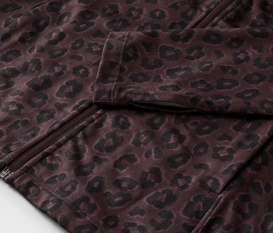 Detail částečně rozepnuté tmavě hnědé bundy s černým leopardím vzorem a zipem.