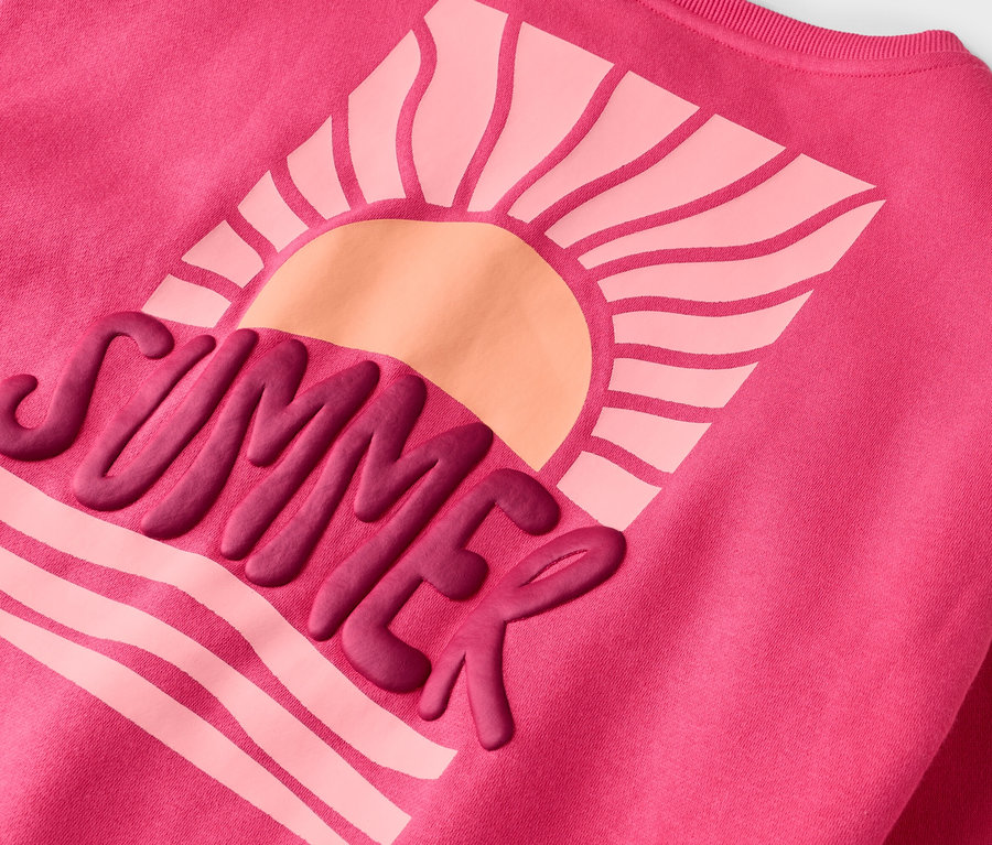 Na růžové mikině je nápis "SUMMER" a motiv slunce.