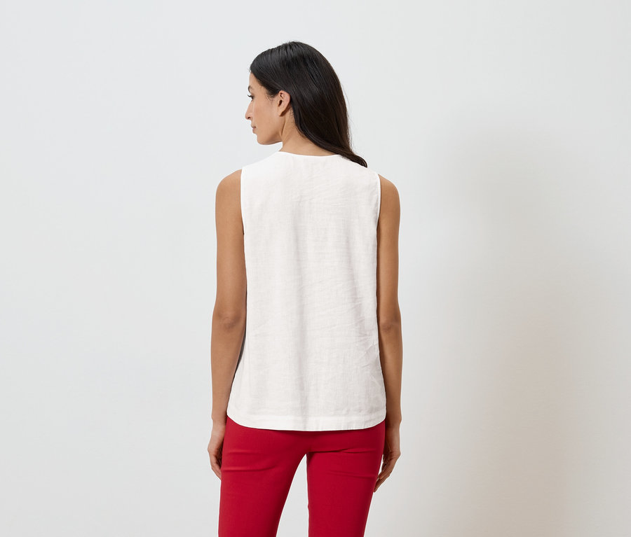 Žena zezadu v tílku a červených kalhotách na bílém pozadí.