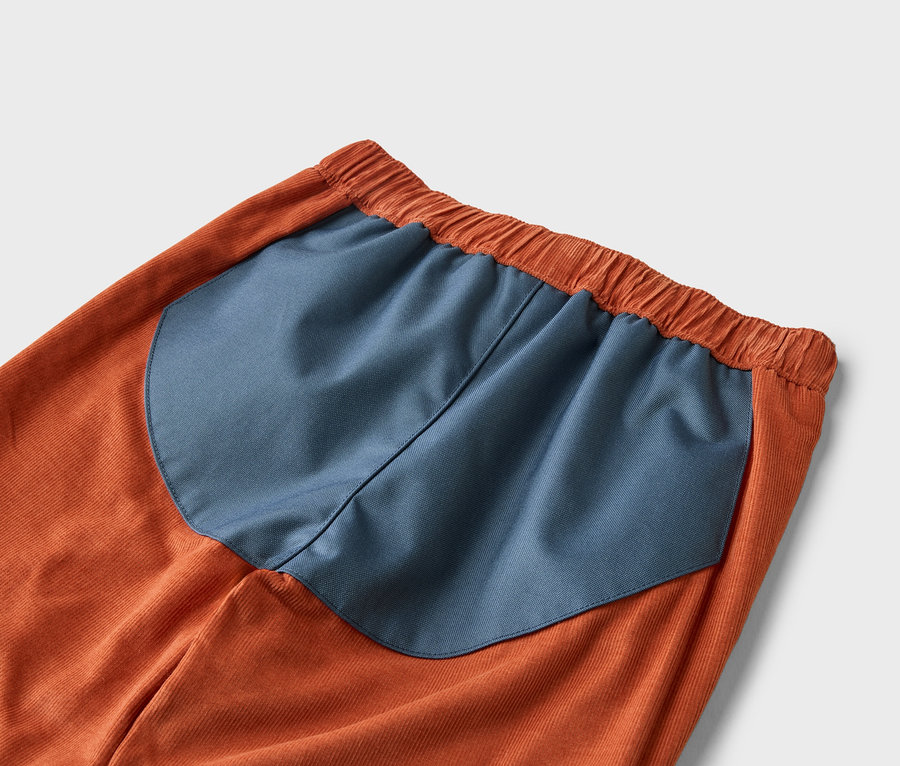 Detail oranžových manšestrových kalhot s tmavě modrou vsadkou v pase.