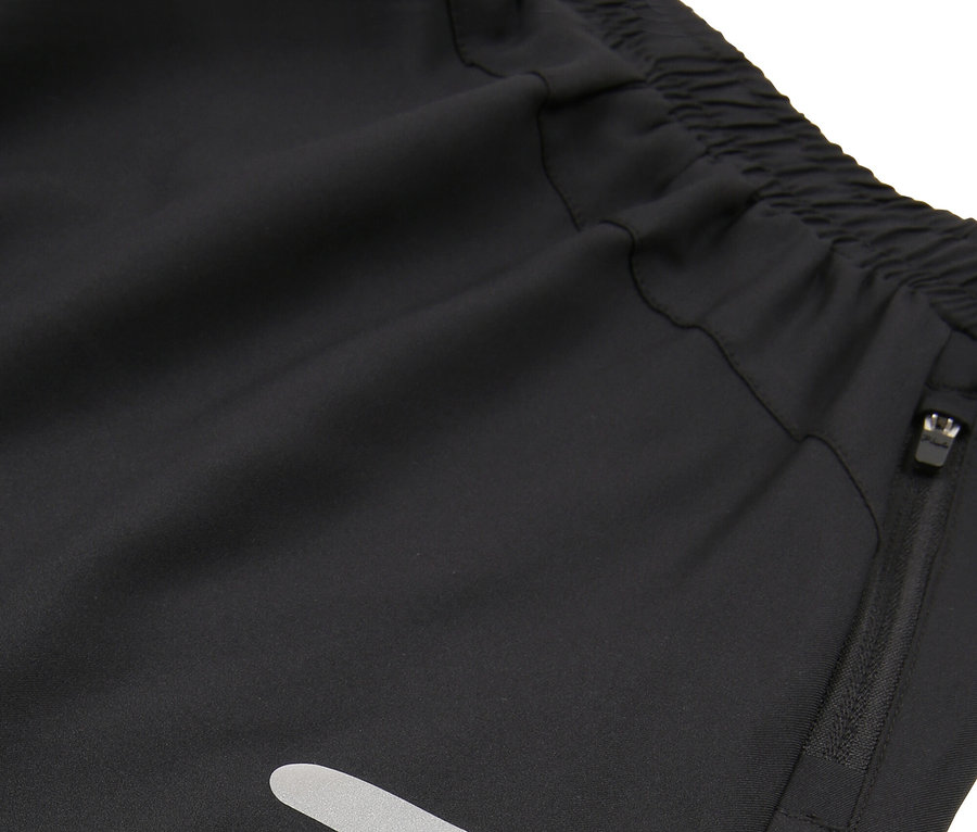 Detail černých šortek s elastickým pasem, kapsou na zip a reflexními pruhy.