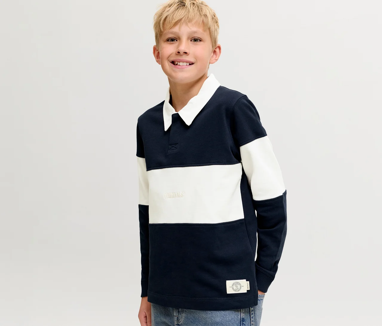 Usmívající se blonďatý chlapec v modro-bílé pruhované polomikině Jack & Jones s bílým límcem.