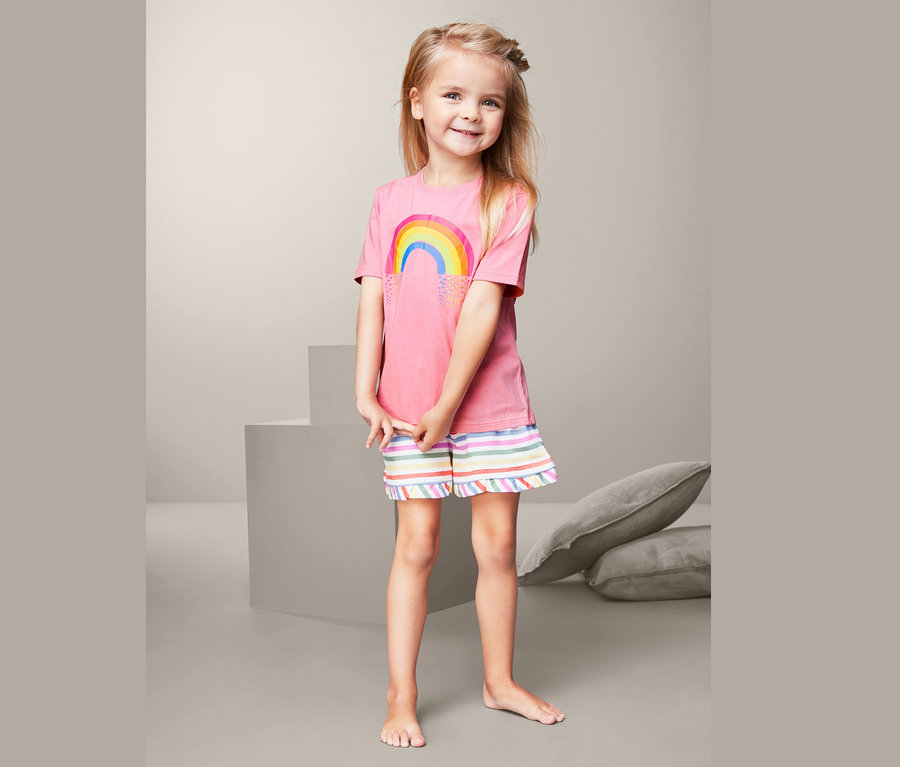 Dívka v pyžamu s duhou na tričku.