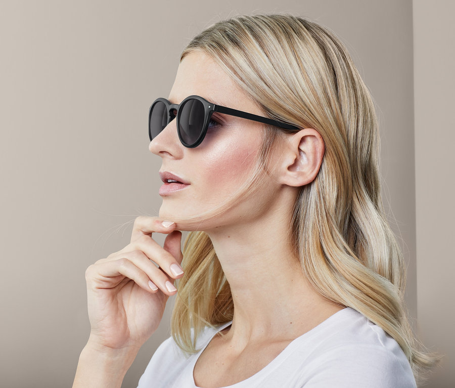 Profil ženy s blond vlasy, která nosí černé sluneční brýle.