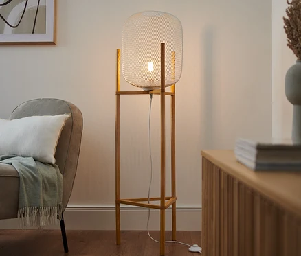 V obývacím pokoji stojí trojnohá stojací lampa.