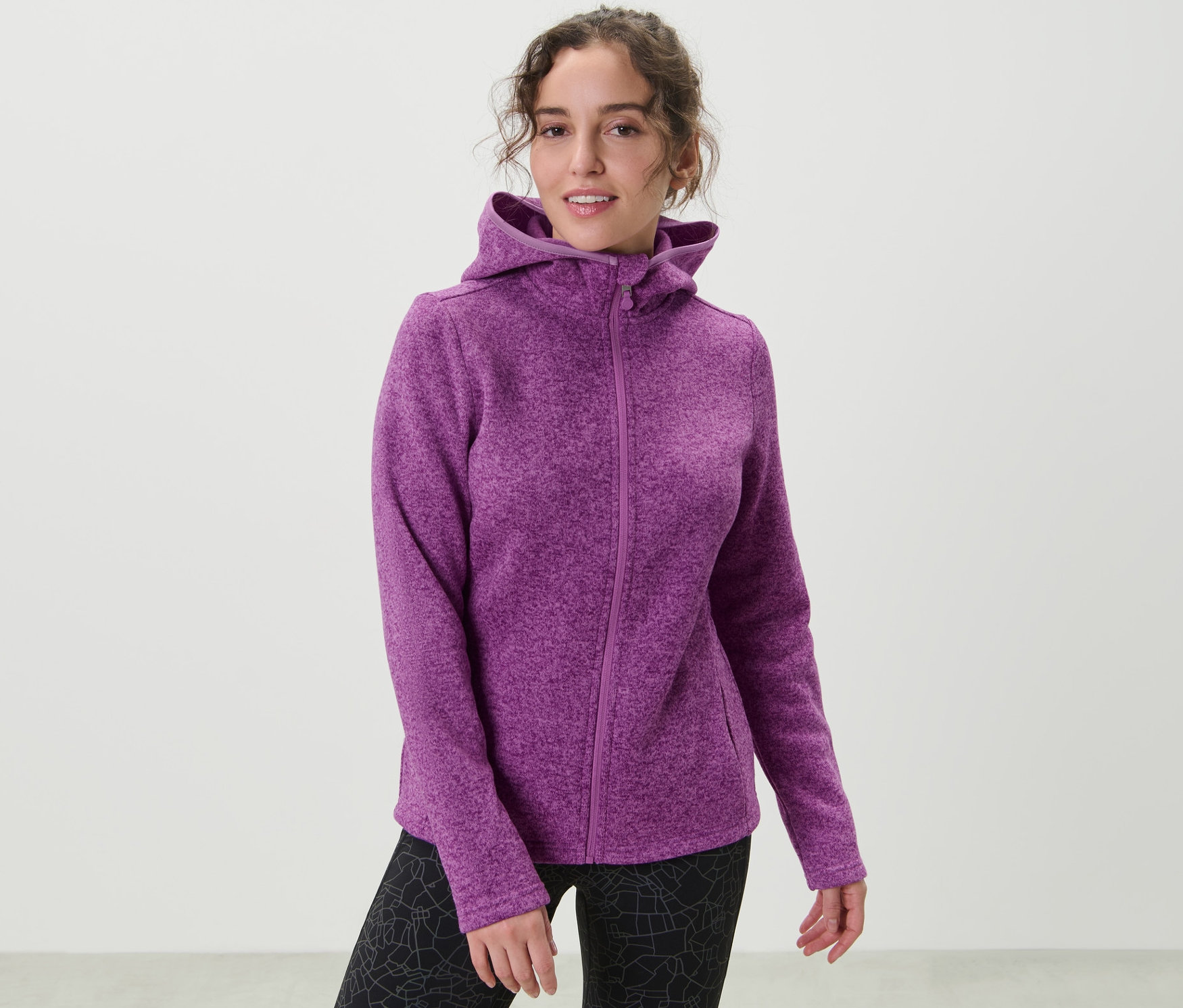 Žena má na sobě bundu z pleteného fleecu, bobulová.